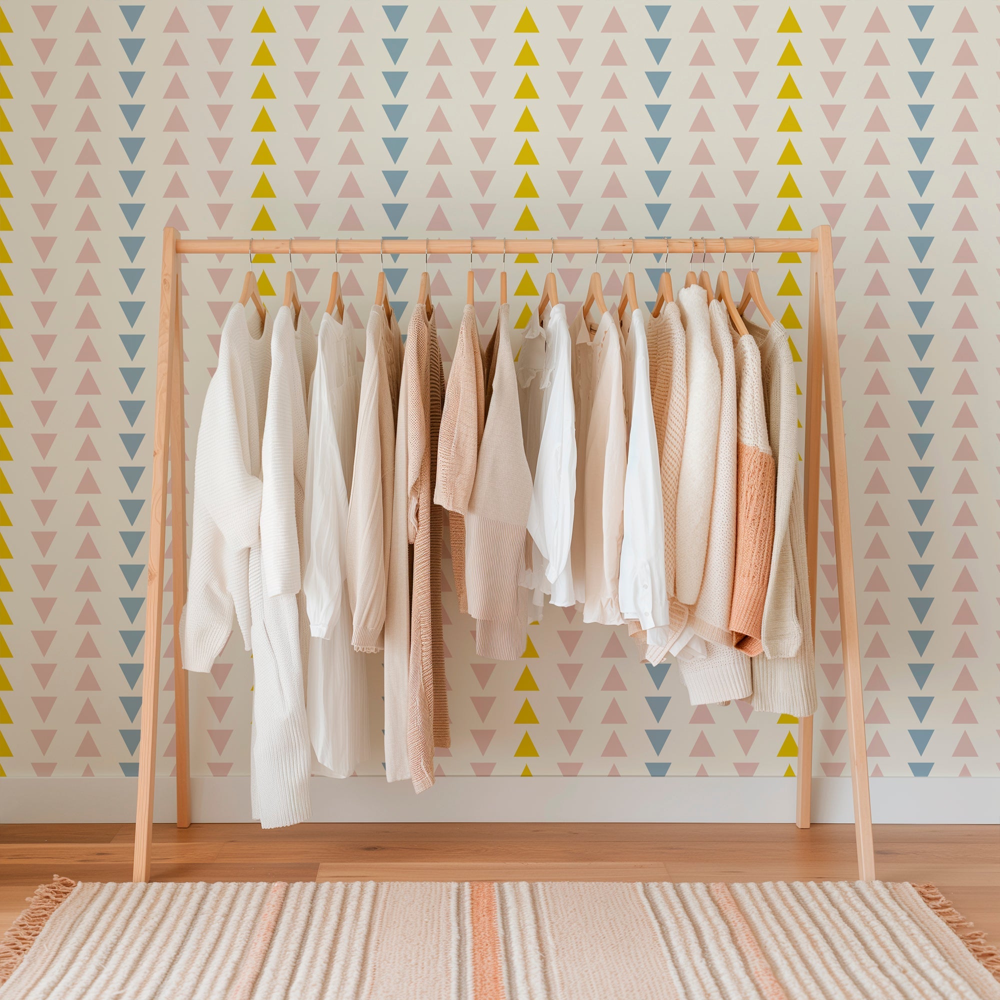 pink blue and yellow arrow geometric wallpaper on a wall behind a rack of clothes