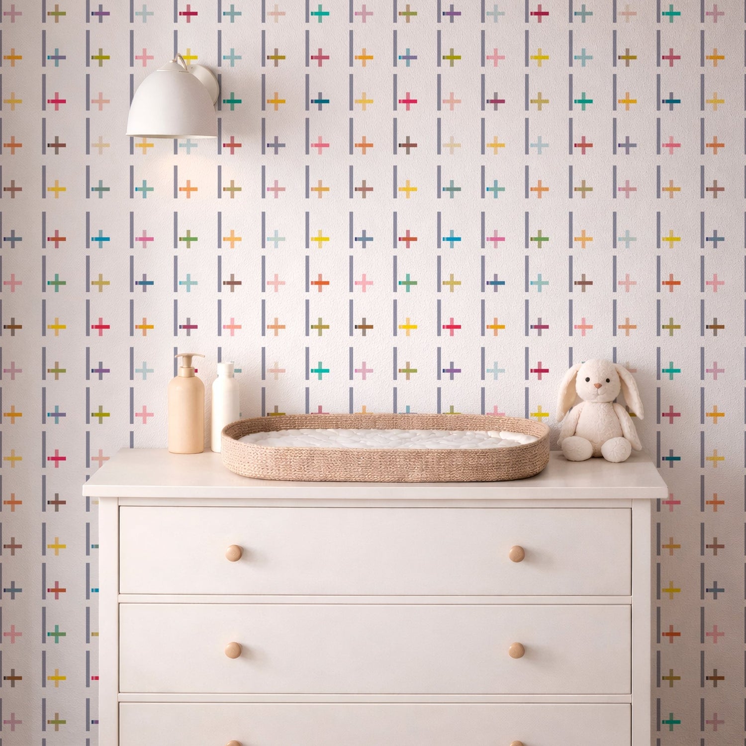 White dresser with a wicker tray, bottle, and plush toy against a multicolored geometric patterned wall.