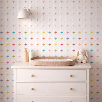 White dresser with a wicker tray, bottle, and plush toy against a multicolored geometric patterned wall.