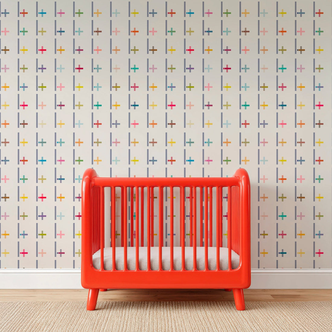Red crib with white mattress against a multicolored geometric patterned wall.