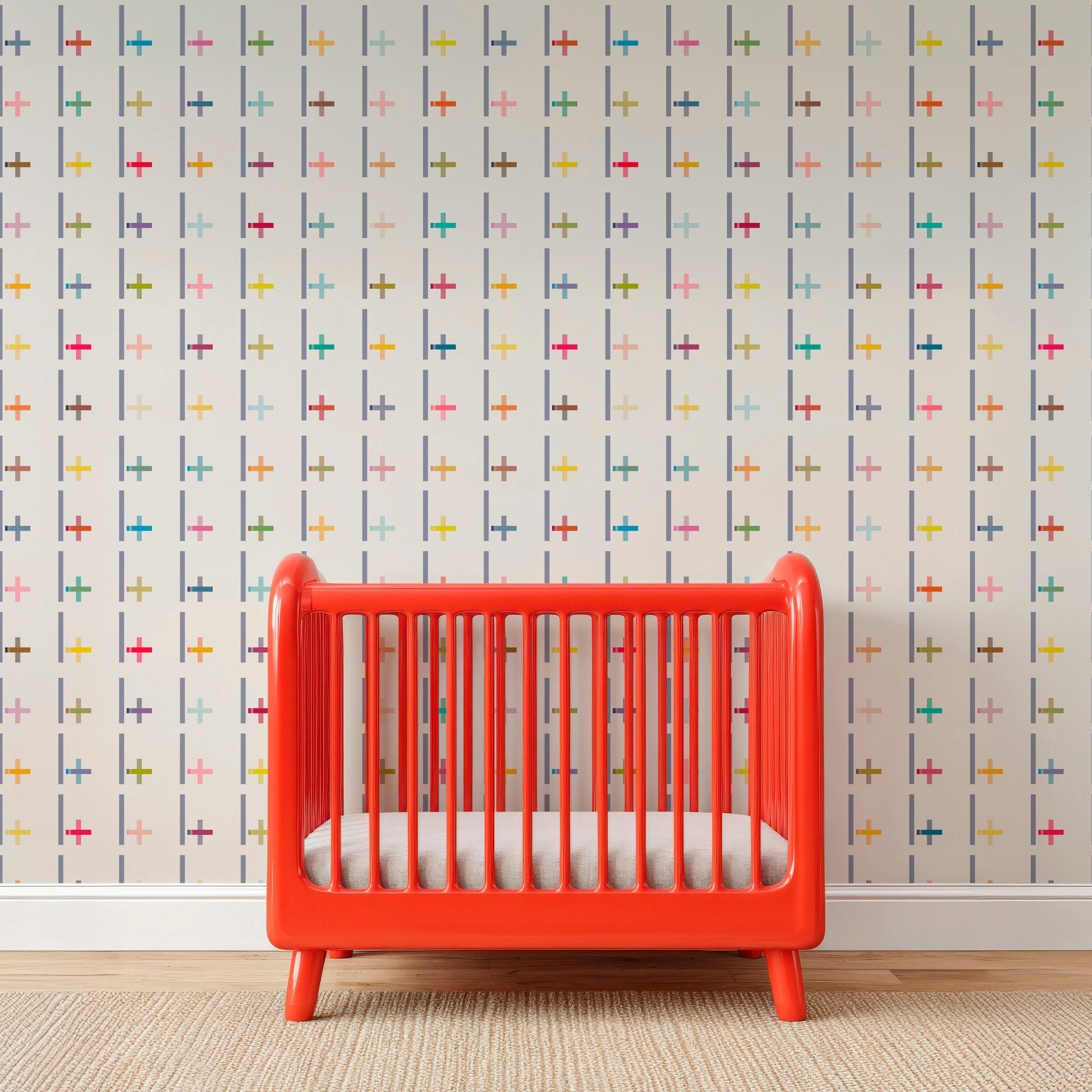 Red crib with white mattress against a multicolored geometric patterned wall.